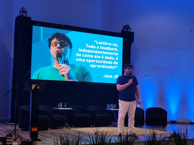 Jose JR en el escenario con una pantalla mostrando una cita sobre feedback